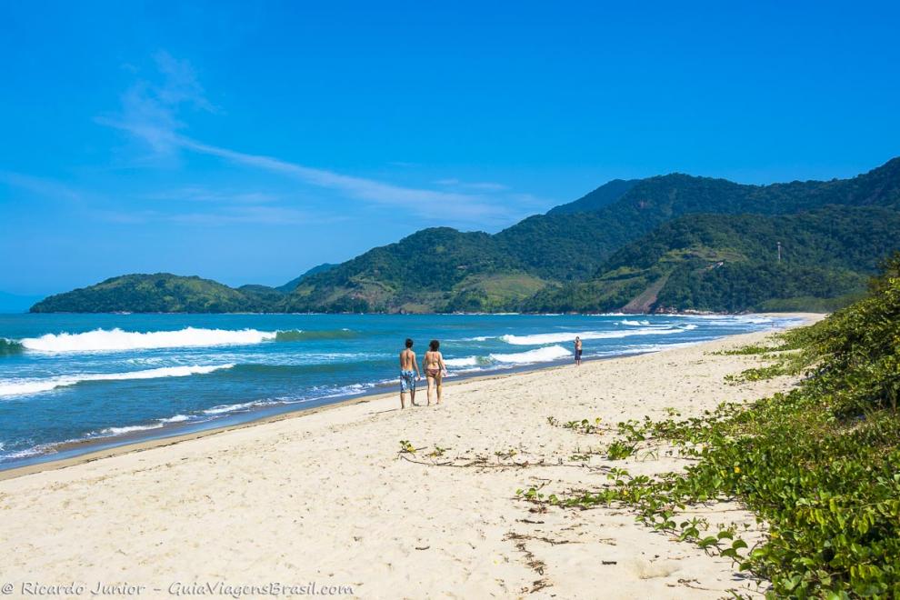 Imagem de mãe e filho caminhando na beira do mar.